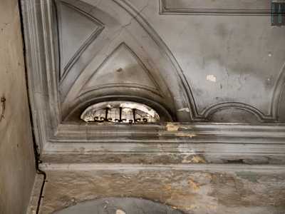 Degli archetti speculari presenti negli angoli formano un elegante comparto decorativo che si completa al centro con una successione concentrica di modanature